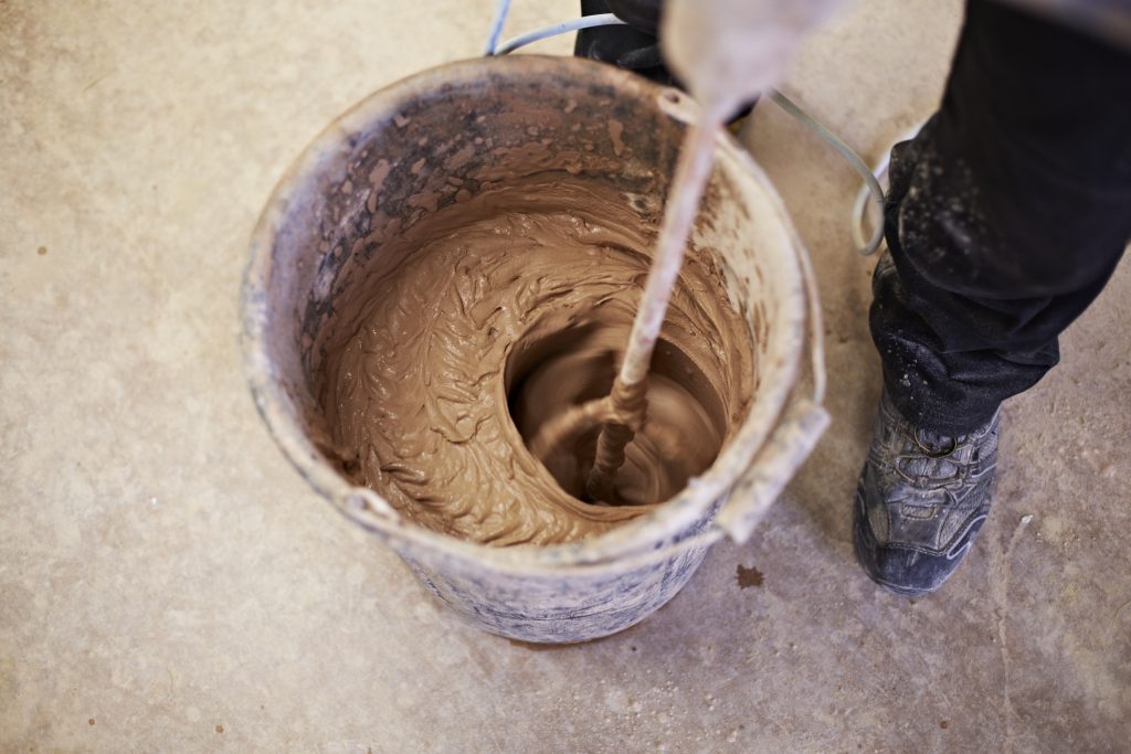 Featured image for 'How do I apply a first coat of plaster' article show bucket with fresh wet plaster being mixed