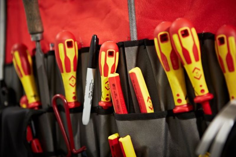 Featured image for article 'How to become a self-employed electrician' shows an electrician's bag full of yellow and red handled tools including screwdrivers and pliers
