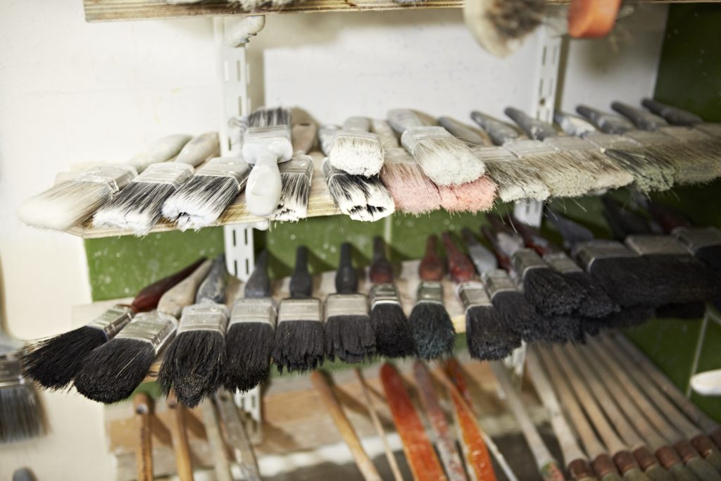 Featured image for article 'Why you should consider a trade as a career change' shows a selection of paint brushes on racks