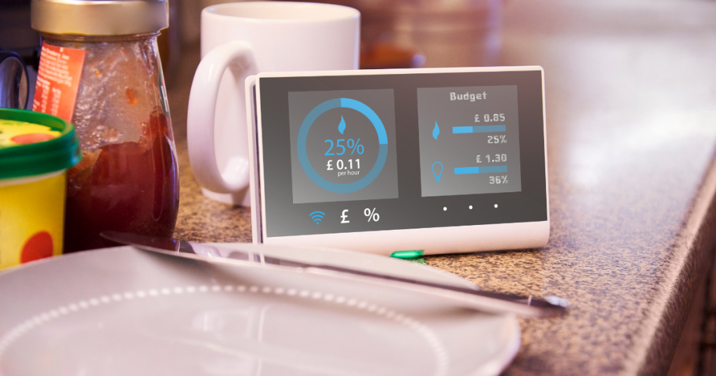 Featured image for article on 'How can I make my home more energy efficient?'. Photo shows a kitchen worktop with a plate, cup and breakfast items of jam and butter, next to a smart meter displaying gas and electricity usage.