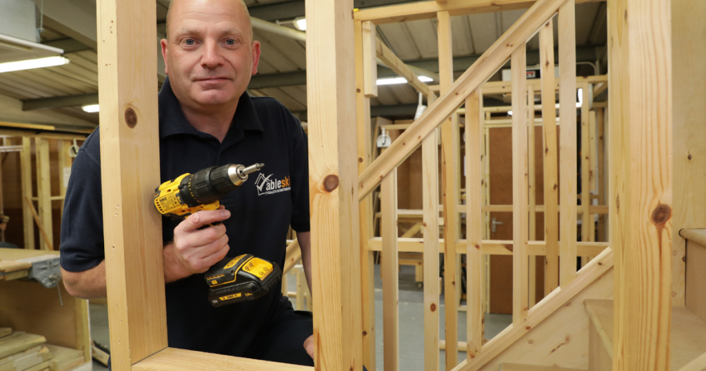 Paul Spencer Carpentry and Joinery Tutor at Able Skills holding a drill and building a balustrade