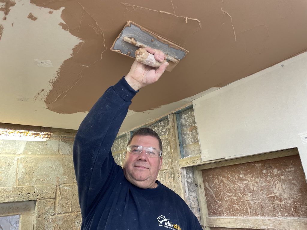 Image shows Jo plastering a ceiling