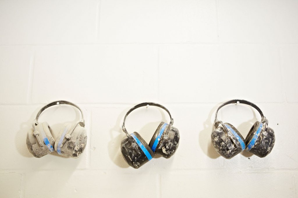 Featured image for article about stress in the construction industry. Image shows three sets of ear defenders on wall hooks.