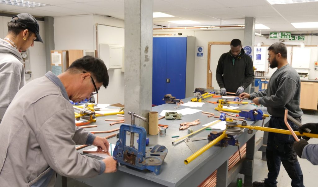 Group of plumbing students bending copper pipes in the Able Skills Construction Training Centre