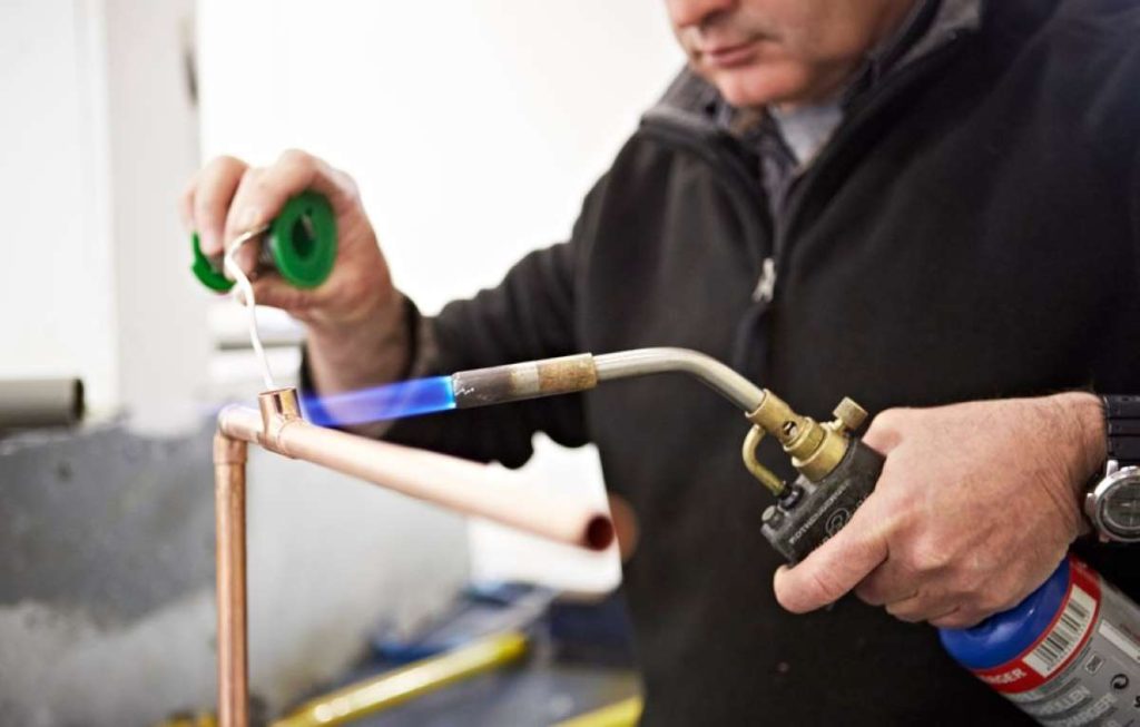 Person soldering copper pipes in the Able Skills construction training centre