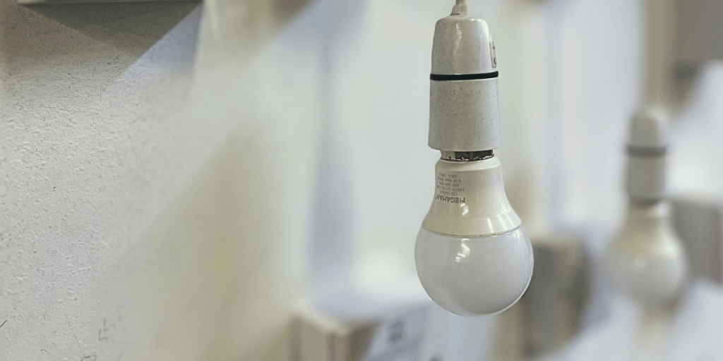 A lightbulb hanging down with switches and another lightbulb in the background