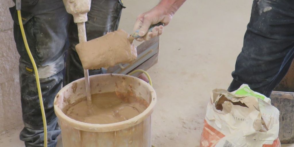 Tow people mixing plaster in a bucket
