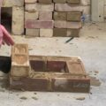 Someone is building a structure out of bricks using a trowel.