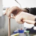 Someone is fixing together pieces of copper piping.