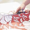 Someone cutting a red flower pattern wallpaper on a trestle table
