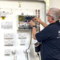 An Able Skills electrical instructor is demonstrating wiring in a fuse box.