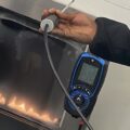 Person holding a gas analyser in front of a gas fire