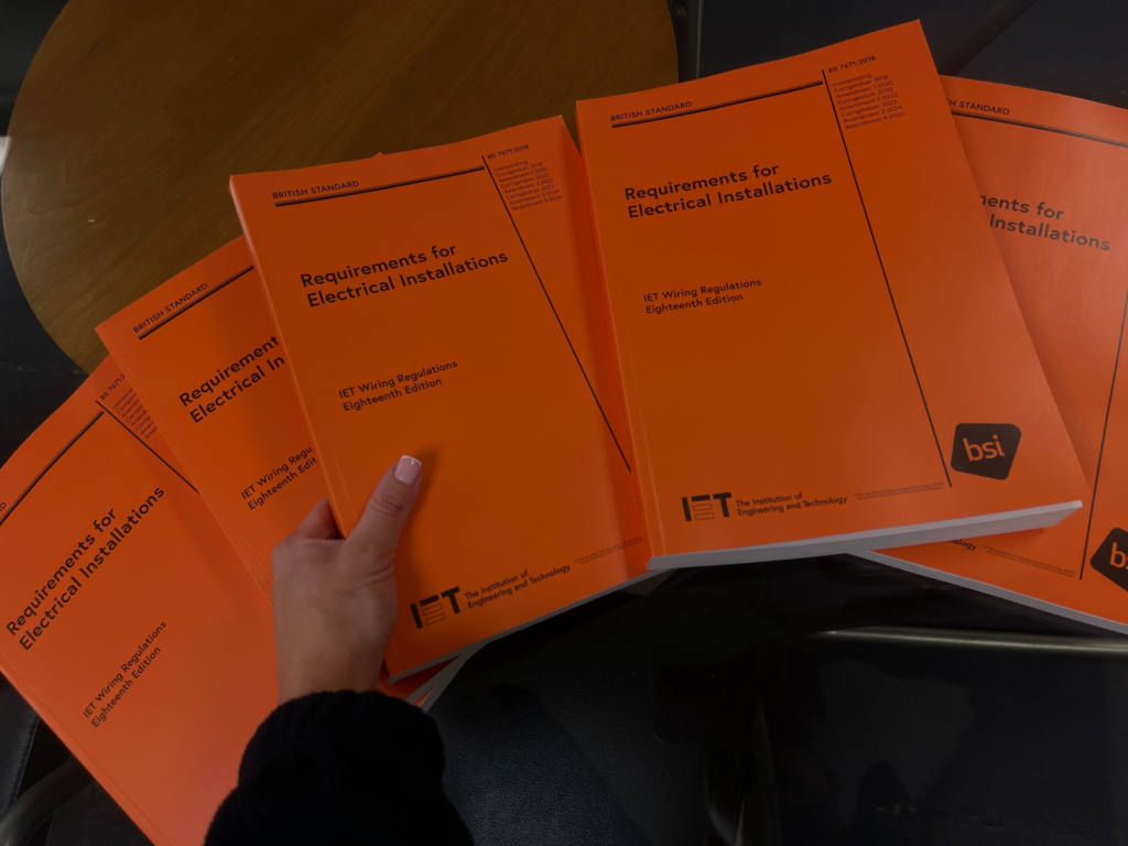 Orange 18th edition books on a desk. A hand is holding one copy