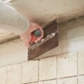 Someone is grouting tiles in a kitchen