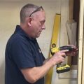 An Able Skills carpentry instructor uses a DeWalkt driver to construct a frame for a wall and door.