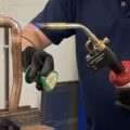 An Able Skills gas instructor is soldering copper pipes